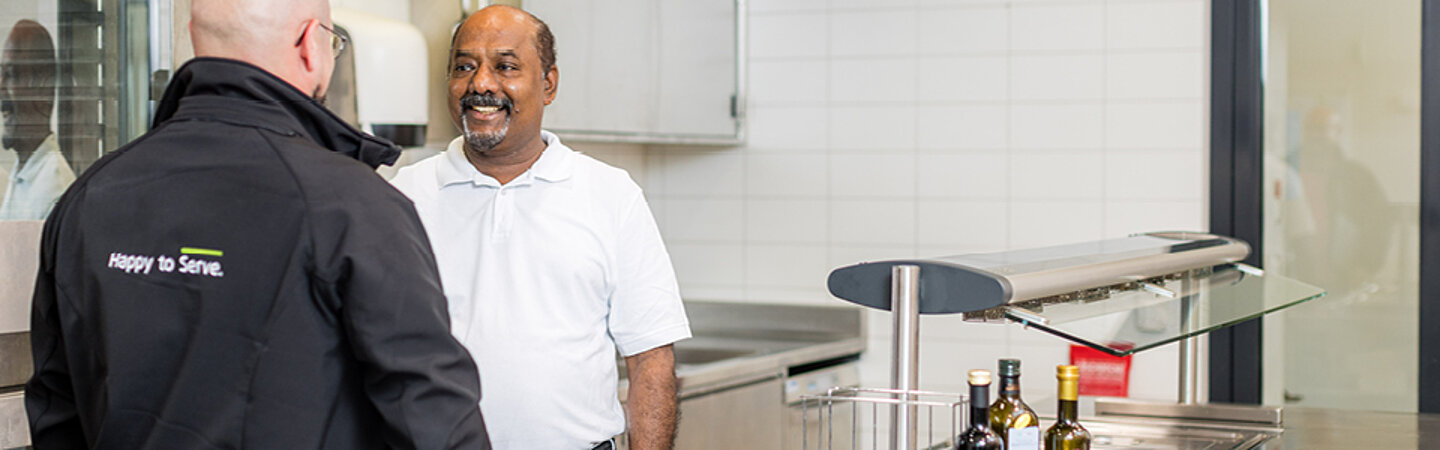 Pacovis-Aussendienstmitarbeiter berät Kunde in einer Kantine